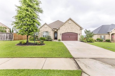 French country home featuring concrete driveway, an attached garage, brick siding, and stone siding