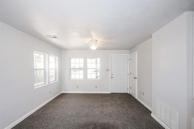 Empty room with dark carpet and ceiling fan