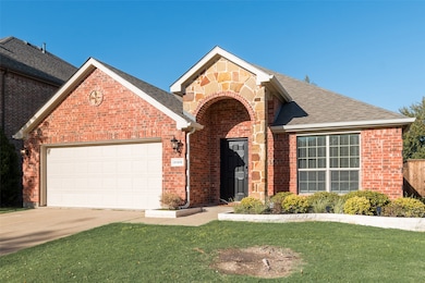 Traditional-style home with brick siding, a front lawn, an attached garage, concrete driveway, and roof with shingles