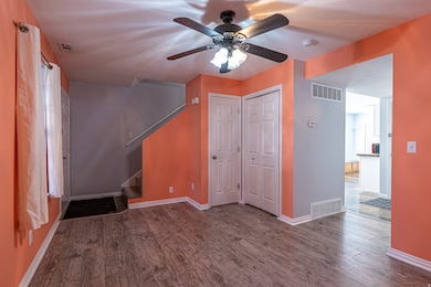 Unfurnished living room featuring dark wood-style flooring, stairway, and ceiling fan