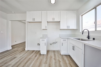 Kitchen with white cabinetry, light wood-style flooring, and light stone counters