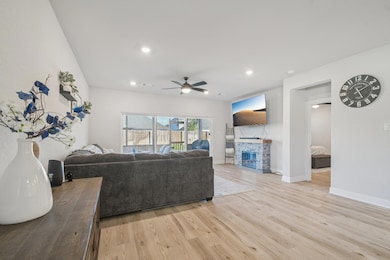 Living area featuring light wood-style floors, a stone fireplace, recessed lighting, and a ceiling fan
