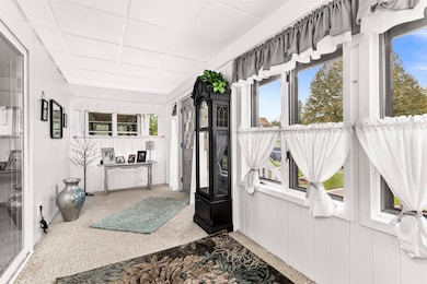 Unfurnished sunroom with a drop ceiling, wood walls, and carpet floors