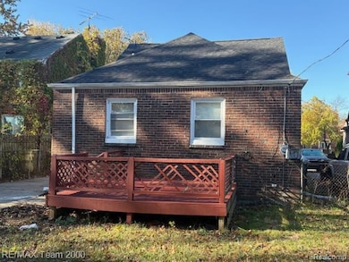 Rear view of property featuring a wooden deck, brick siding, and roof with shingles