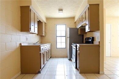 Kitchen with sink, range with electric cooktop, light tile patterned flooring, and a textured ceiling