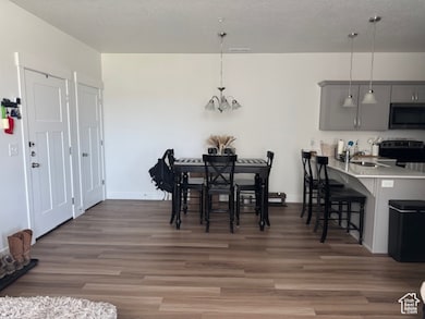 Dining room featuring dark wood-type flooring, a textured ceiling, and a chandelier