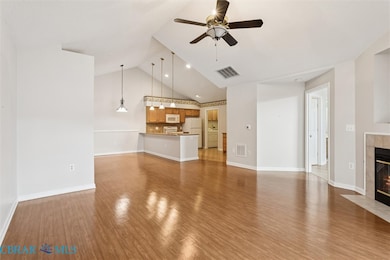 Unfurnished living room featuring light wood-type flooring, a tile fireplace, high vaulted ceiling, and ceiling fan