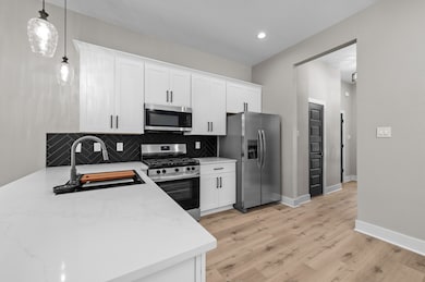 This modern kitchen features white cabinetry, stai