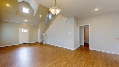 Unfurnished living room with high vaulted ceiling, stairway, light wood finished floors, and recessed lighting