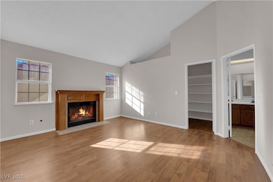 Unfurnished living room with high vaulted ceiling, light wood-style floors, and a fireplace with flush hearth