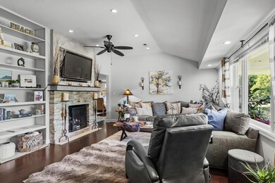 Living area with vaulted ceiling, wood finished floors, a ceiling fan, a premium fireplace, and recessed lighting
