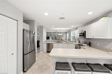 Kitchen with kitchen peninsula, stainless steel appliances, decorative light fixtures, and light tile patterned floors