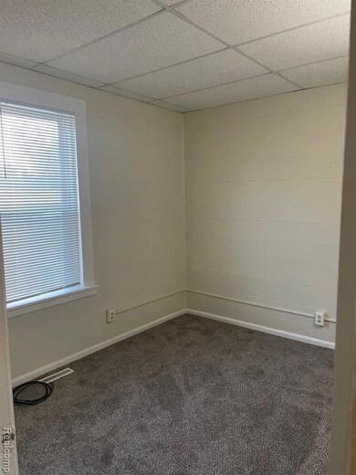 Carpeted spare room featuring baseboards and a paneled ceiling