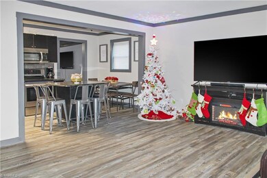 Living Room to kitchen with new LVP flooring, raised ceilings, and trim.
