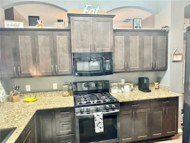 Kitchen with black microwave, range with gas stove