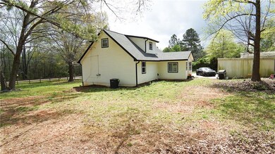 Back of property featuring roof with shingles, central AC, fence, and a lawn