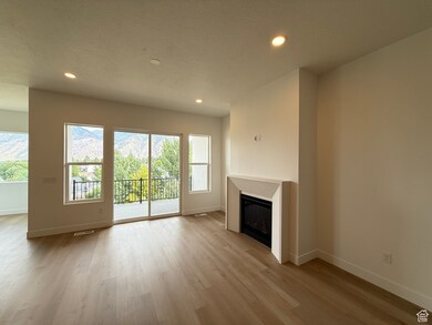 Unfurnished living room with a glass covered fireplace, light wood finished floors, recessed lighting, and a textured ceiling