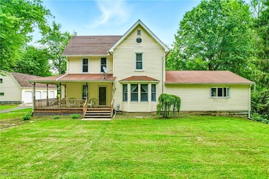 Back of house featuring a porch, a yard, and roof with shingles