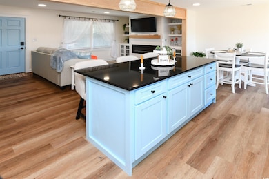 Kitchen featuring open floor plan, dark countertops, light wood-type flooring, a breakfast bar, and a kitchen island