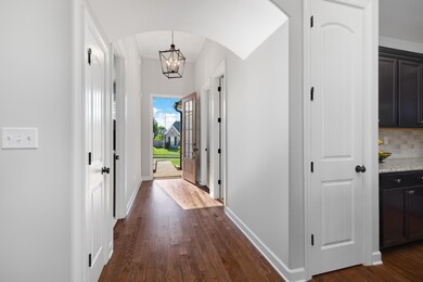 Hall featuring a notable chandelier and dark wood-