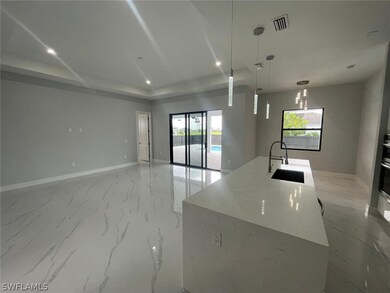 Kitchen featuring hanging light fixtures, sink, light stone counters, a center island with sink, and light tile patterned floors