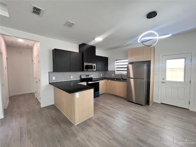 Kitchen featuring backsplash, a peninsula, appliances with stainless steel finishes, and visible vents