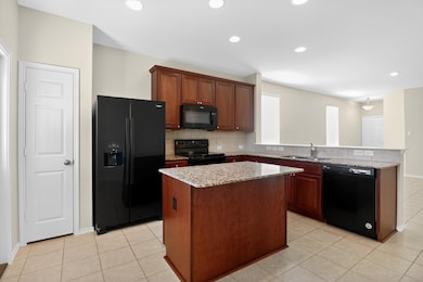 Kitchen featuring tasteful backsplash, black appliances, light tile patterned floors, a kitchen island, and recessed lighting