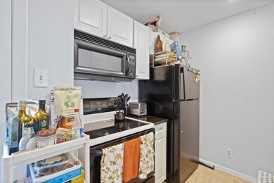 Kitchen with black appliances, white cabinetry, b