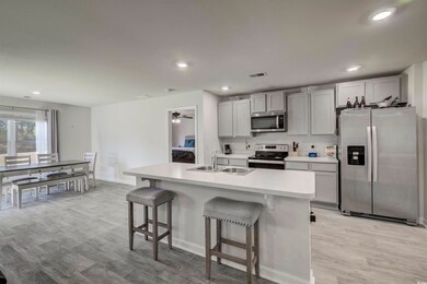 Kitchen featuring light wood-style flooring, appliances with stainless steel finishes, a kitchen bar, and a sink