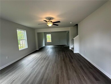 Unfurnished living room with dark wood-style floors, a ceiling fan, and stairs