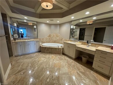 Bathroom featuring ornamental molding, a garden tub, two vanities, coffered ceiling, and recessed lighting