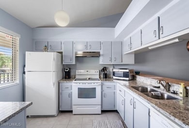 Kitchen with white appliances, a sink, under cabin