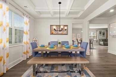 Dining area with wood finished floors, crown molding, baseboards, a chandelier, and coffered ceiling