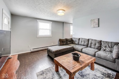 living area featuring wood finished floors, a textured ceiling, and a baseboard radiator