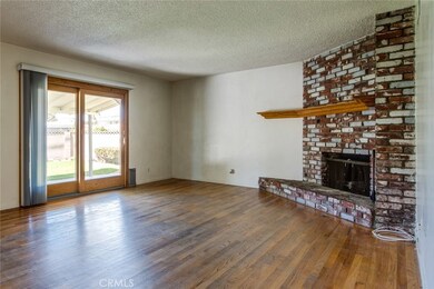 Spacious and open living room has a beautiful used brick corner fireplace and original hardwood floors.