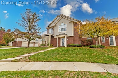Traditional home with a balcony, brick siding, a front yard, and a garage