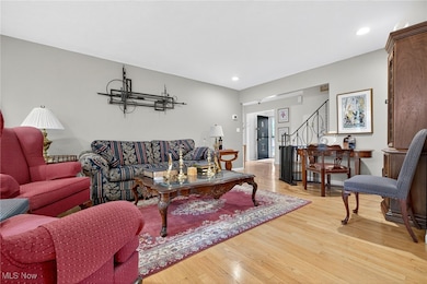 Living room featuring light wood-style flooring, recessed lighting, and stairway