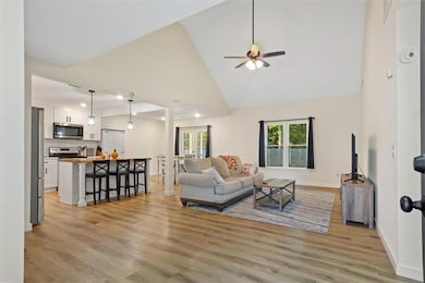 Living area featuring high vaulted ceiling, light wood-style flooring, and ceiling fan