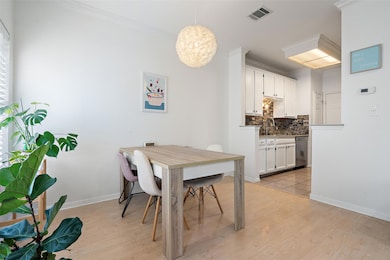 Dining space featuring light wood-type flooring, a chandelier, and crown molding