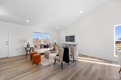 Living area with recessed lighting, high vaulted ceiling, and light wood-style floors