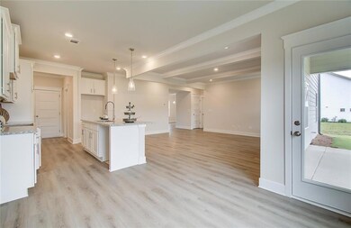 Kitchen with a sink, beamed ceiling, open floor plan, recessed lighting, and white cabinetry