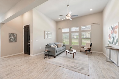 Living room featuring a ceiling fan, light wood-s