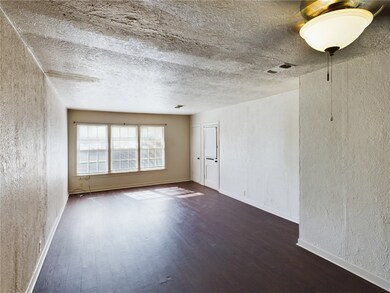 Spare room with a textured wall, dark wood-type fl