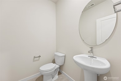 Powder room features elongated toilet and pedestal sink. Photo is representational. Actual home is under construction and materials, colors, and finishes will vary. See site agent for details.