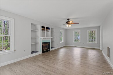Unfurnished living room featuring ceiling fan, light wood-type flooring, and built in shelves