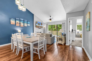 Dining area with a ceiling fan, wood finished floors, lofted ceiling, baseboards, and a textured ceiling