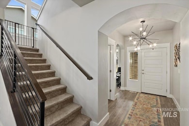 Foyer entrance featuring a chandelier, arched walkways, stairway, and wood finished floors