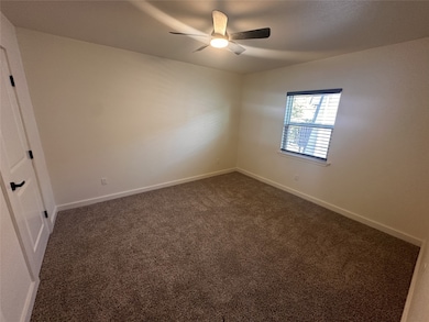 Empty room featuring dark carpet and ceiling fan