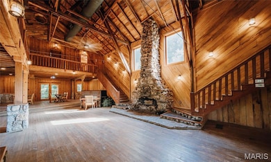 Unfurnished living room featuring high vaulted ceiling, wood walls, stairway, a wooden ceiling with exposed beams, and hardwood / wood-style floors