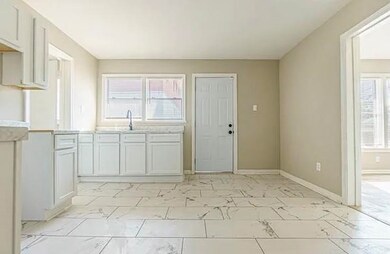Kitchen featuring light marble finish flooring, light countertops, and white cabinets